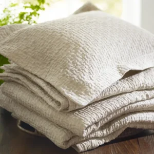 SDH Purists Eton oatmeal textured linen fabric sample folded with sham on wood surface.
